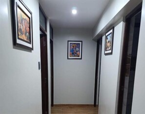 A hallway with framed artwork on the walls, a central light fixture, and wooden flooring. - Amazing 5-bedroom apartment in Cusco perfect for your getaway (Cusco)