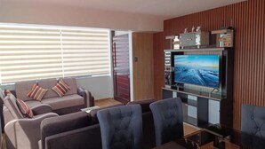 A modern living room with a flat-screen TV, a sofa, and a dining area. - Amazing 5-bedroom apartment in Cusco perfect for your getaway (Cusco)
