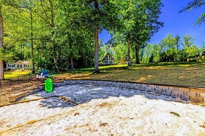 A backyard with a brick wall, a green inflatable pool, and a house in the background. - Lake Anna A-Frame | Beach, Dock & Hot Tub | 5BR (Bumpass)