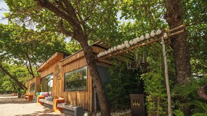 A modern wooden building with large windows, outdoor seating, and a stone pathway. - Casa De La Puerta Azul (San Felipe Puerto Plata)