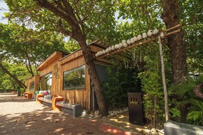 A modern wooden building with large windows, outdoor seating, and a stone pathway. - Casa De La Puerta Azul (San Felipe Puerto Plata)