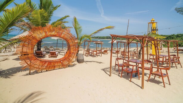 A beach with a circular wooden structure, beach chairs, and umbrellas. - Casa De La Puerta Azul (San Felipe Puerto Plata)