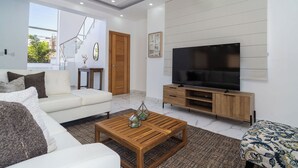 A modern living room with a sofa, coffee table, TV, and a staircase. - Casa De La Puerta Azul (San Felipe Puerto Plata)