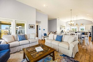 Ein geräumiges Wohnzimmer mit zwei Sofas, einem Couchtisch und einem Essbereich, mit einer Küche im Hintergrund.