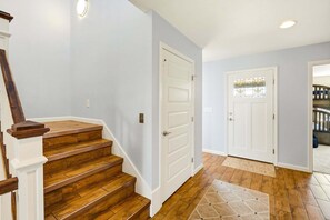 A staircase with wooden steps and white walls, leading to a door with a glass panel. - Oceanfront Retreat w/ Panoramic Views (Kitty Hawk)