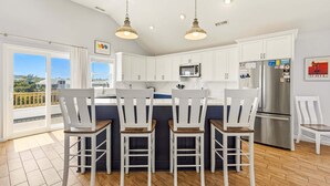 Een moderne keuken met witte kastjes, een roestvrijstalen koelkast en een groot eiland met barstoelen.