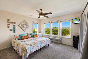A bedroom with a bed, a ceiling fan, a TV, and a window with a view. - Oceanfront Retreat w/ Panoramic Views (Kitty Hawk)