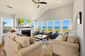 A living room with a fireplace, a television, and a view of the ocean. - Oceanfront Retreat w/ Panoramic Views (Kitty Hawk)