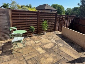 A patio with a table and chairs, a wooden fence, and potted plants. - 1BR House with Terrace for 2 and 1 Parking Space (Bristol City)