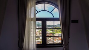 Ein Fenster mit Blick auf eine Stadt, Vorhänge und ein Schild an der Wand.
