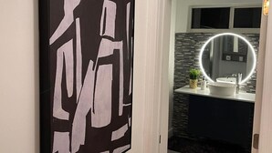 A modern bathroom with a round mirror, a white sink, and a dark countertop. - luxury cozy apartment for couples only (Hallandale Beach)