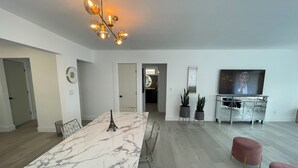 A modern living room with a marble dining table, a chandelier, a television, and a potted plant. - luxury cozy apartment for couples only (Hallandale Beach)