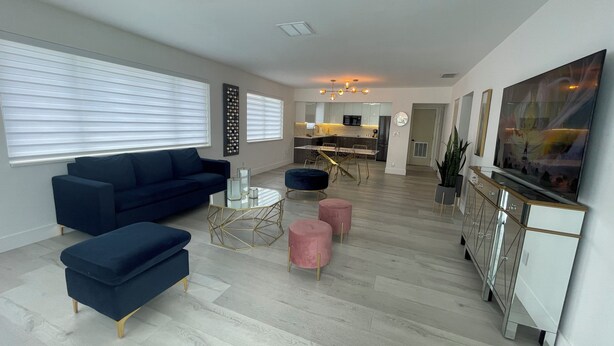 A modern living room with a sofa, ottoman, coffee table, and a TV. - luxury cozy apartment for couples only (Hallandale Beach)