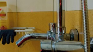 Une salle de bain avec un robinet chromé, un distributeur de savon et un porte-serviettes.