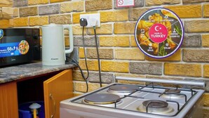 Une cuisine équipée d’un four à micro-ondes, d’une tasse à café, d’une prise de courant murale et d’une cuisinière.