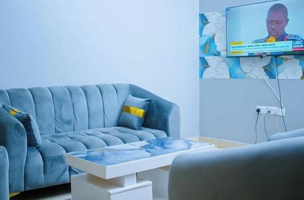 Un saló modern amb un sofà gris, una taula de centre blanca i una televisió de pantalla plana penjada a la paret.