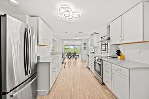 Una cocina moderna con armarios blancos, electrodomésticos de acero inoxidable y suelo de madera.