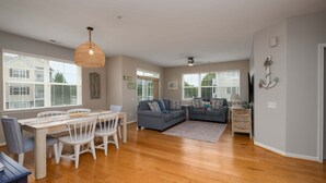 A spacious living area with a dining table, two sofas, and a ceiling fan. - End of the Season Special! Beautiful Rehoboth Beach Condo Pools Tennis Parking (Rehoboth Beach)