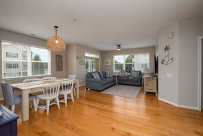 A spacious living area with a dining table, two sofas, and a ceiling fan. - Beautiful Rehoboth Beach Condo Pools Tennis Parking (Rehoboth Beach)