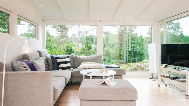 A modern living room with a sofa, ottoman, and a TV. - 4 Star Holiday Home in Silkeborg (Silkeborg)