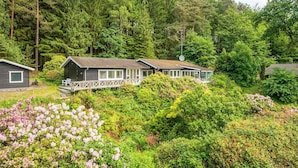 A cabin with a deck, surrounded by dense forest and flowering shrubs. - 4 Star Holiday Home in Silkeborg (Silkeborg)