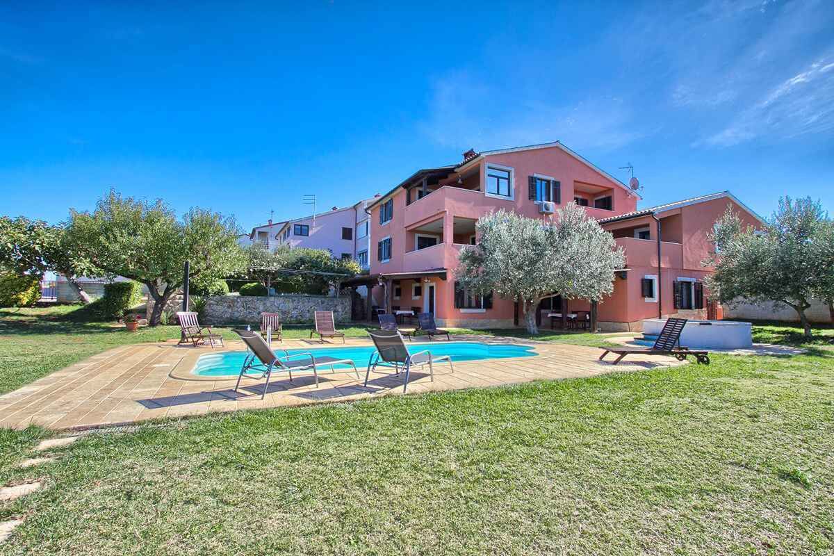 A multi-story building with a swimming pool, outdoor seating, and a well-maintained lawn.