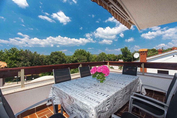 A balcony with a table covered in newspaper, chairs, and a vase of flowers. - Holiday apartment near the sea for 6 people (Punat)