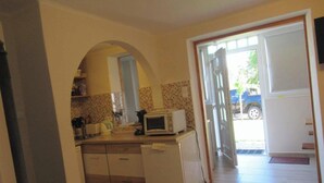 Cozinha equipada com micro-ondas, torradeira e frigorífico. Uma porta dá para o exterior.