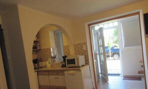 A kitchen with a microwave, a toaster, and a refrigerator. There is a doorway leading outside. - Holiday home with pool and air conditioning (Csopak)
