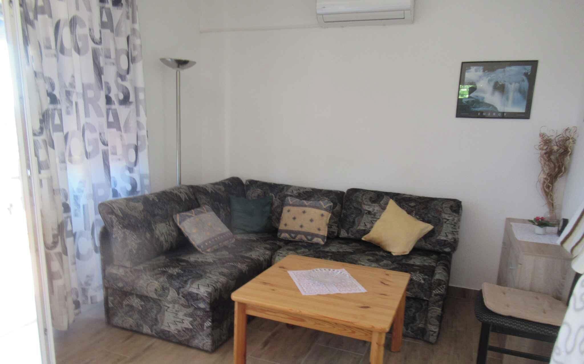 Een woonkamer met een gestreept bankstel, een houten salontafel, een vloerlamp en een ingelijst schilderij aan de muur.