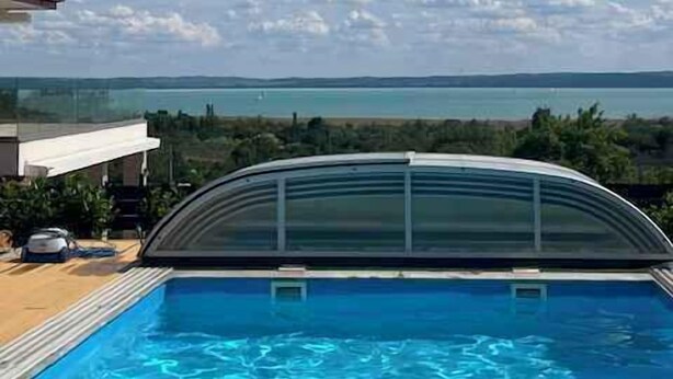 Piscina com vista clara para o mar e montanhas ao longe.