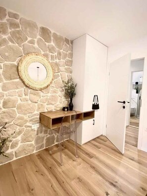Ein Zimmer mit einer Steinwand, einem Holzkonsolentisch, einem weißen Kleiderschrank und einer Tür.