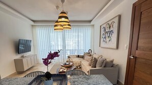 Una sala de estar moderna con una isla central, un conjunto de sofás, un televisor y un cuadro en la pared.