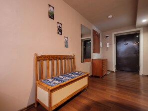 Ein Zimmer mit einer Holzbänke, einem Spiegel, einem Schrank und einer Tür.