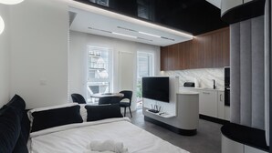 Moderni hotellihuone, jossa on sänky, televisio, työpöytä ja näkymä kaupunkiin.