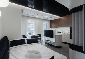 Ein modernes Hotelzimmer mit Bett, Fernseher, Schreibtisch und Blick auf die Stadt.