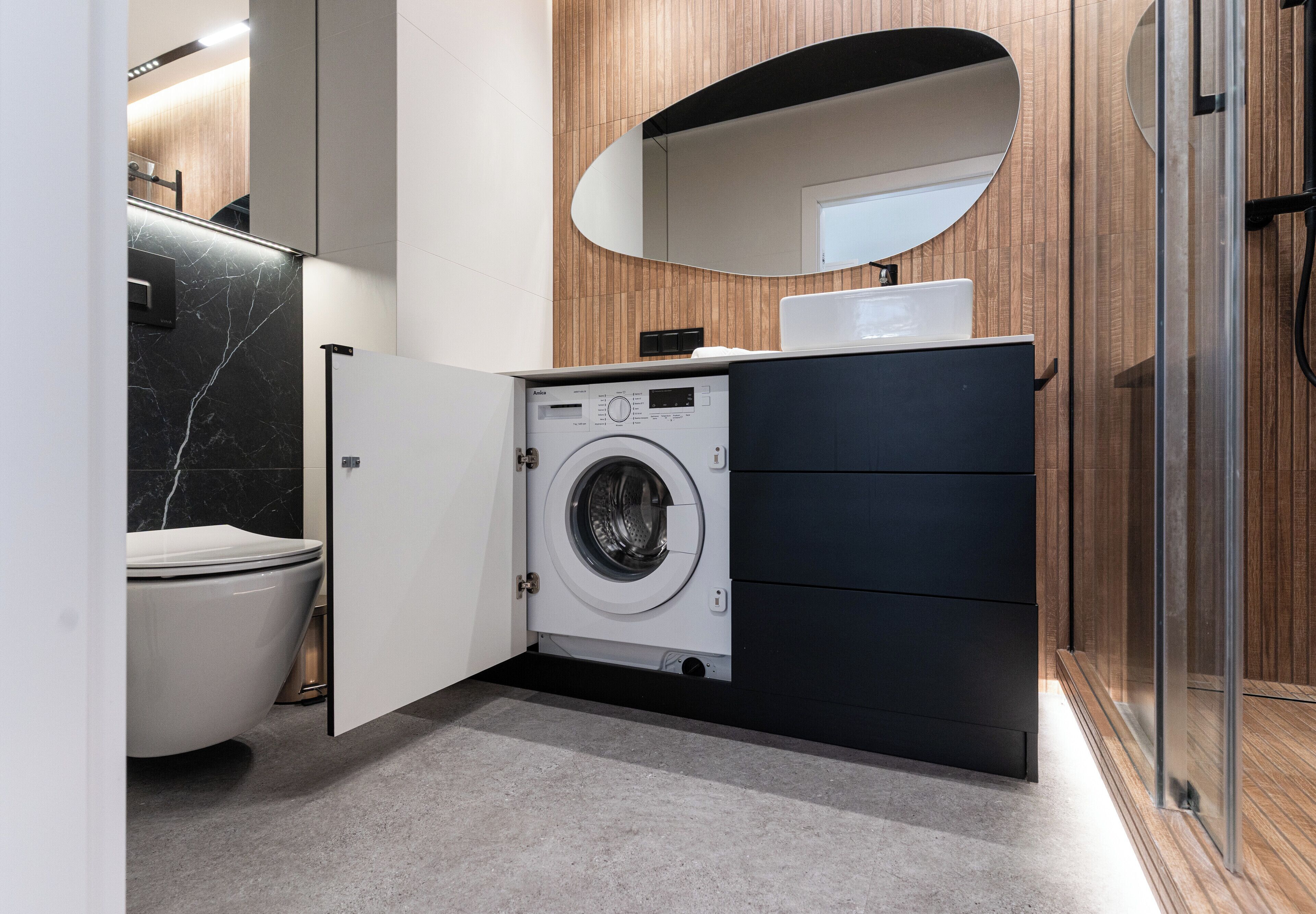 Un bagno compatto dotato di lavatrice, un water, un lavandino e uno specchio.