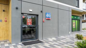 Ein modernes Gebäude mit Glastür, einem blauen Schild mit der Nummer 44 und einer grünen Tür rechts.