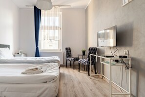 A hotel room with a bed, two chairs, a desk with a TV, and a window with curtains. - Gdańsk Hostel Octopus Studio #1 (Gdańsk)