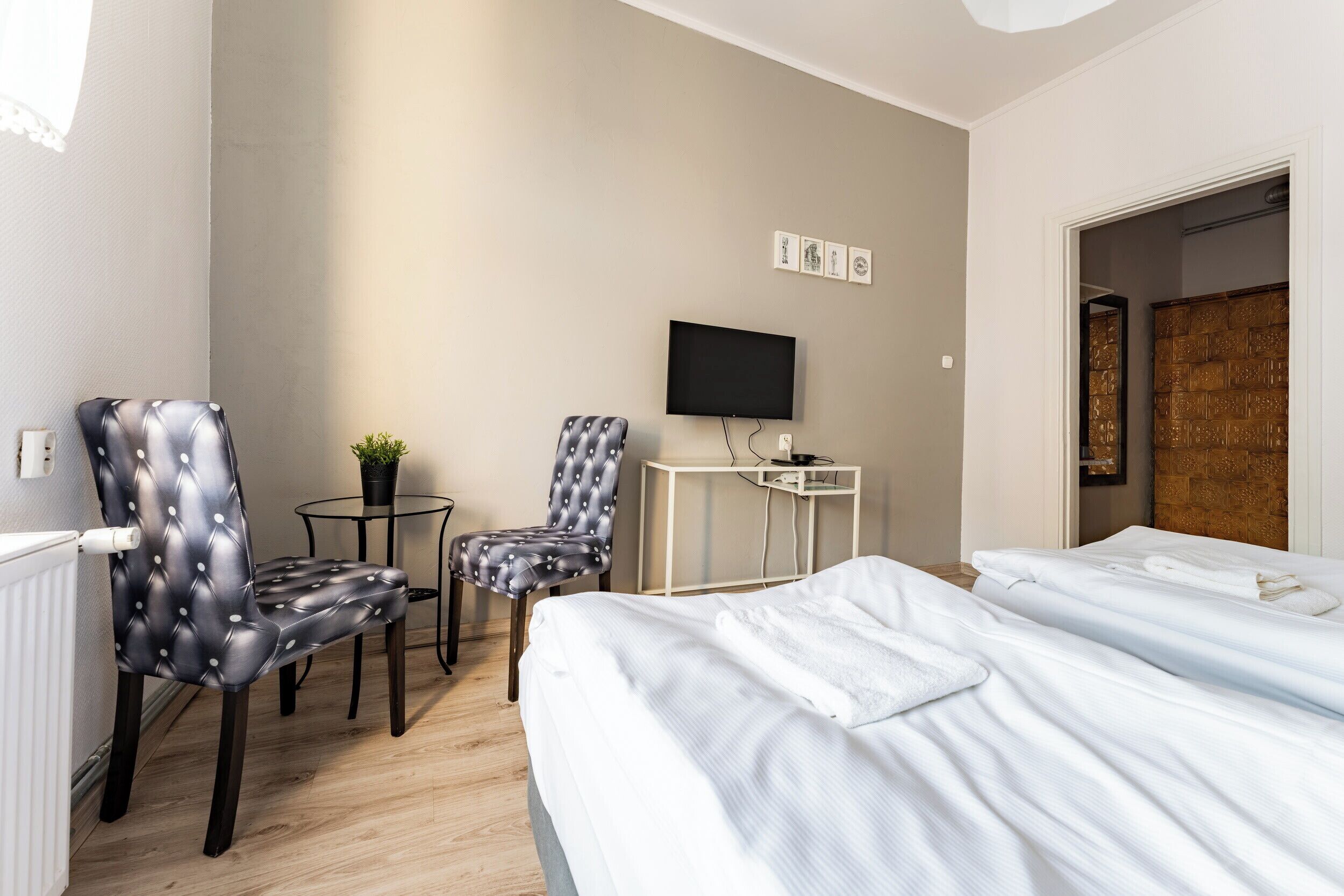 Une chambre d’hôtel avec deux lits, une télévision, une petite table avec une plante et une chaise.