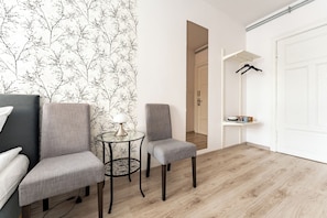 A room with two grey chairs, a small round table with a lamp, a white door, and a coat rack. - Gdańsk Hostel Octopus Studio #2 (Gdańsk)