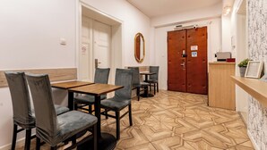 A dining area with a wooden table and chairs, a mirror, and a patterned floor. - Gdańsk Hostel Octopus Studio #3 (Gdańsk)