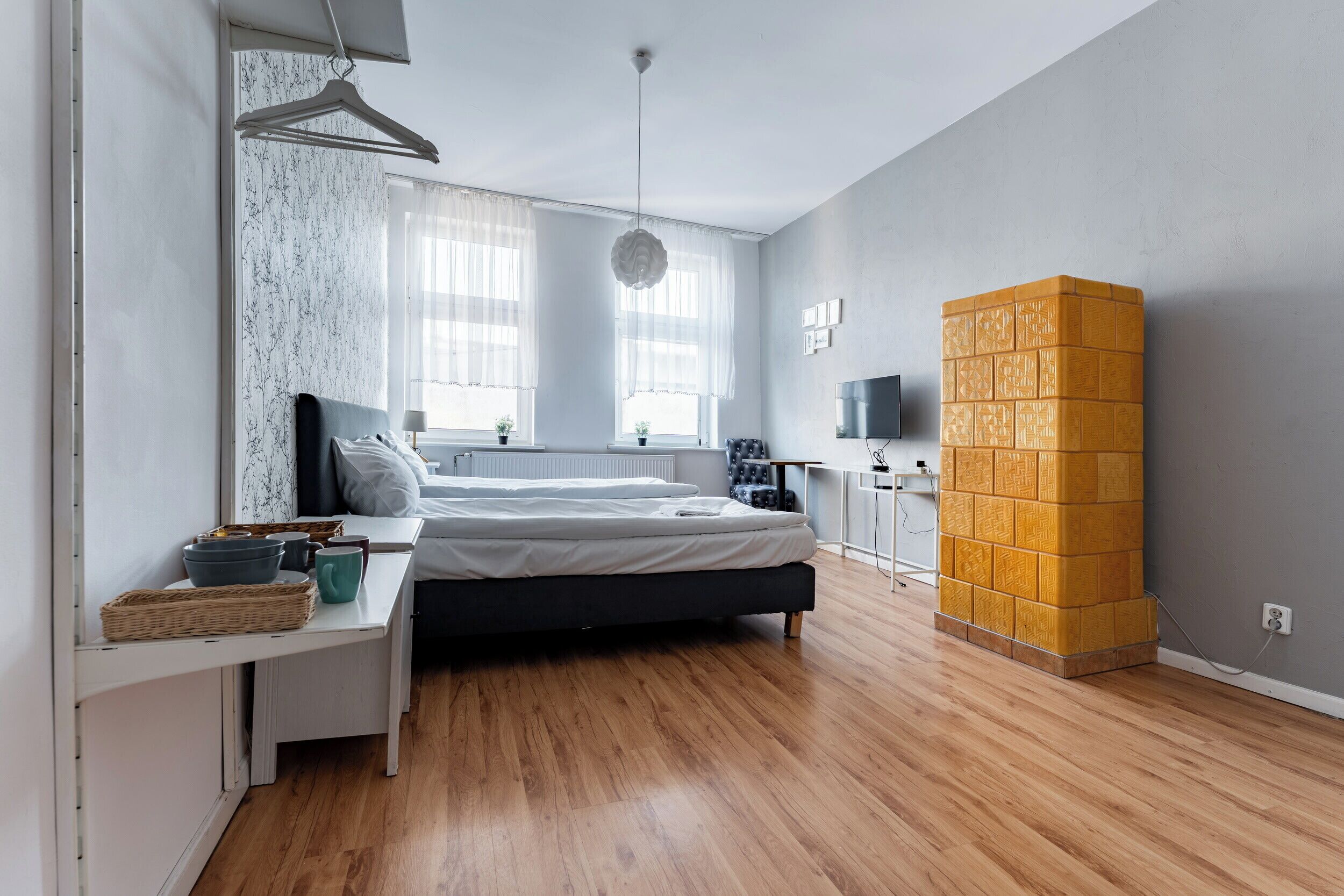 Un dormitorio con cama, mesita de noche y televisor instalado en la pared.
