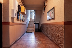 A hallway with a tiled floor, a staircase, and a wall-mounted bulletin board. - Gdańsk Hostel Octopus Studio #3 (Gdańsk)