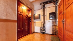 A hallway with wooden doors, a tiled floor, a wall-mounted thermostat, and a fire alarm. - Gdańsk Hostel Octopus Studio #3 (Gdańsk)