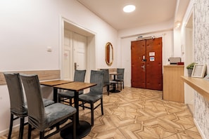 A dining area with a wooden table and chairs, a mirror, and a patterned floor. - Gdańsk Hostel Octopus Studio #4 (Gdańsk)