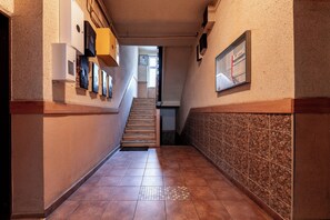 A hallway with a tiled floor, a staircase, and a wall-mounted bulletin board. - Gdańsk Hostel Octopus Studio #4 (Gdańsk)