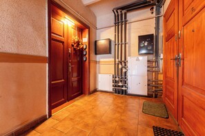 A hallway with wooden doors, a tiled floor, a wall-mounted thermostat, and a fire alarm. - Gdańsk Hostel Octopus Studio #4 (Gdańsk)