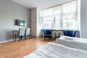 A hotel room with a wooden floor, a bed, a desk with a chair, a TV, and a window with curtains. - Gdańsk Hostel Octopus Studio #5 (Gdańsk)