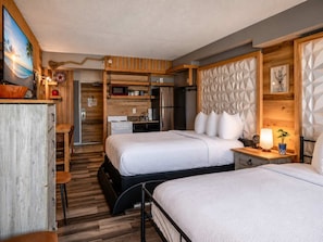 Ein kleines Zimmer mit zwei Betten, einer Küchenzeile und einem Essbereich.